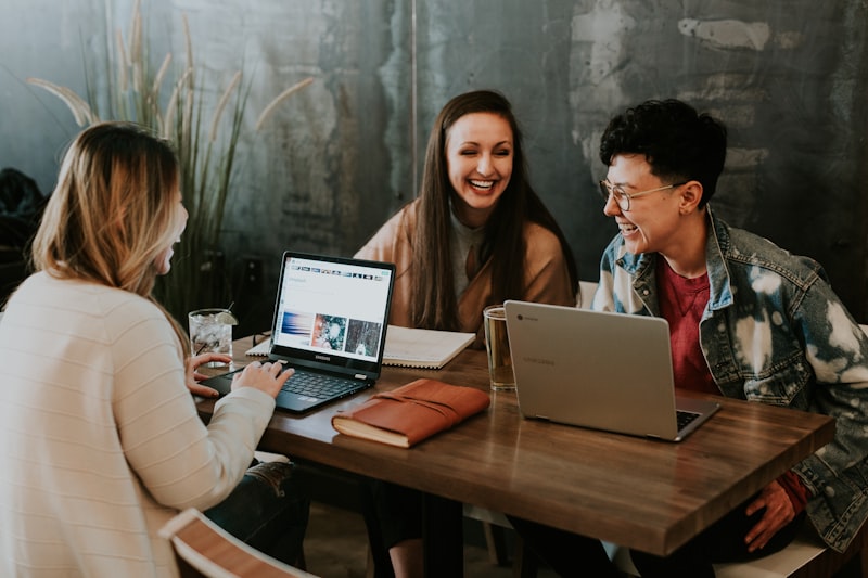 People laughing and coding together at a cafe